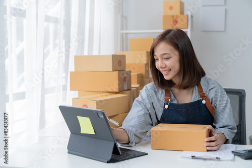SME entrepreneur Small business entrepreneurs Online selling ideas, Happy Asian business owner work on computer and a box at home, delivery SME procurement package box deliver to customers,