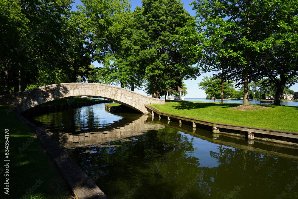 Stone walking bridge arches over a river through a community park. Stone walking bridge arches over a river through a community park.