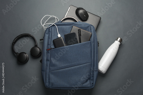 Laptop with Modern gadgets and accessories for work and study in Backpack on dark gray background. Top view. Flat lay