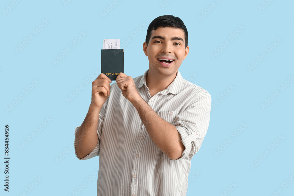 Happy young man with passport on blue background