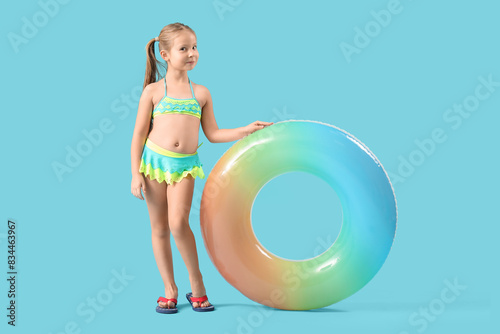 Cute little girl in swimsuit with inflatable ring on blue background © Pixel-Shot