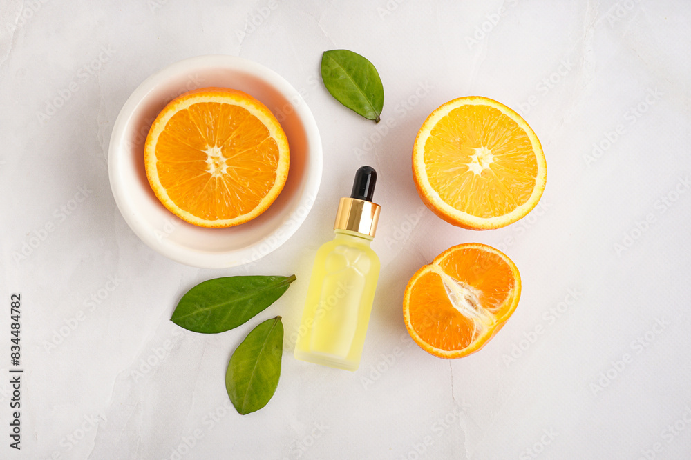 Composition with bottle of essential oil and fresh orange on grey background