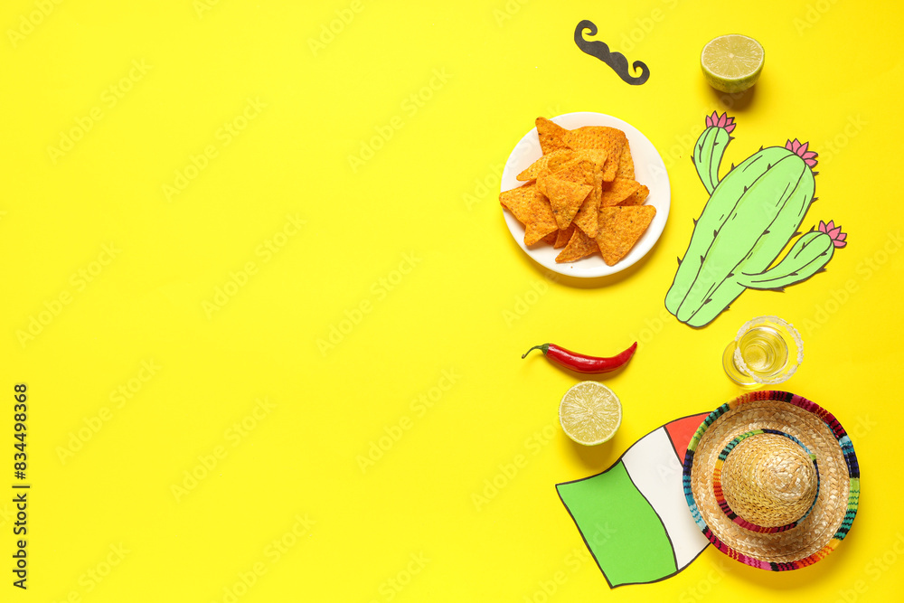 Sombrero with nachos, lime and paper decor on yellow background. Cinco de Mayo Sombrero with nachos, lime and paper decor on yellow background. Cinco de Mayo