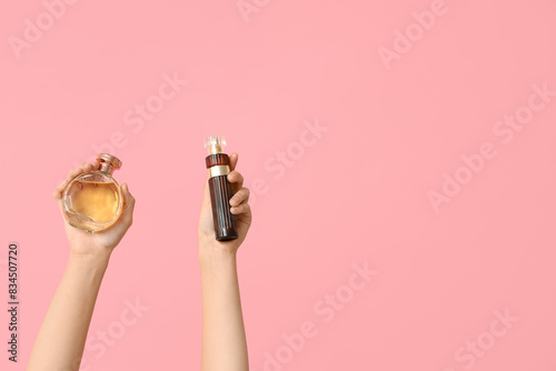 Female hands with bottles of perfume on pink background