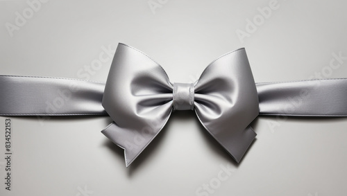 A silver bow with a long ribbon on a pale gray background. photo