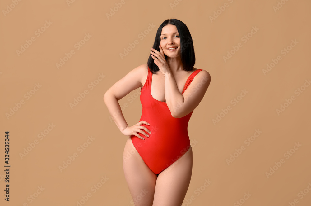 Beautiful young woman in stylish red swimsuit on brown background Beautiful young woman in stylish red swimsuit on brown background