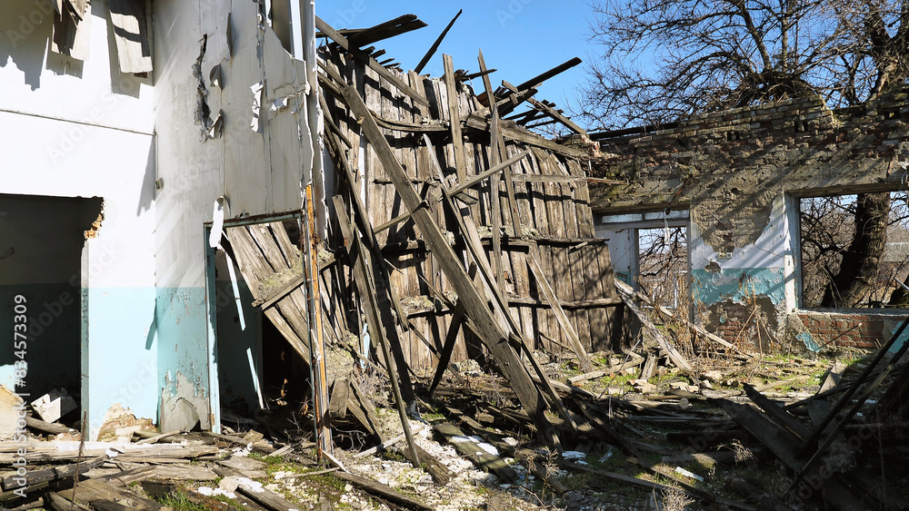 A dilapidated, abandoned building with significant structural damage. Wooden beams and walls have collapsed and debris is scattered on the ground. The surrounding area shows signs of neglect. A dilapidated, abandoned building with significant structural damage. Wooden beams and walls have collapsed and debris is scattered on the ground. The surrounding area shows signs of neglect.