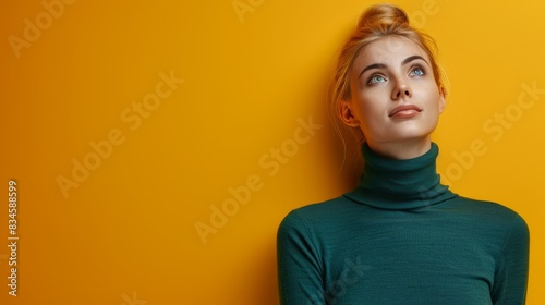  A woman with red hair wears a green turtleneck, facing a yellow wall She tilts her head to the side, gazing up photo
