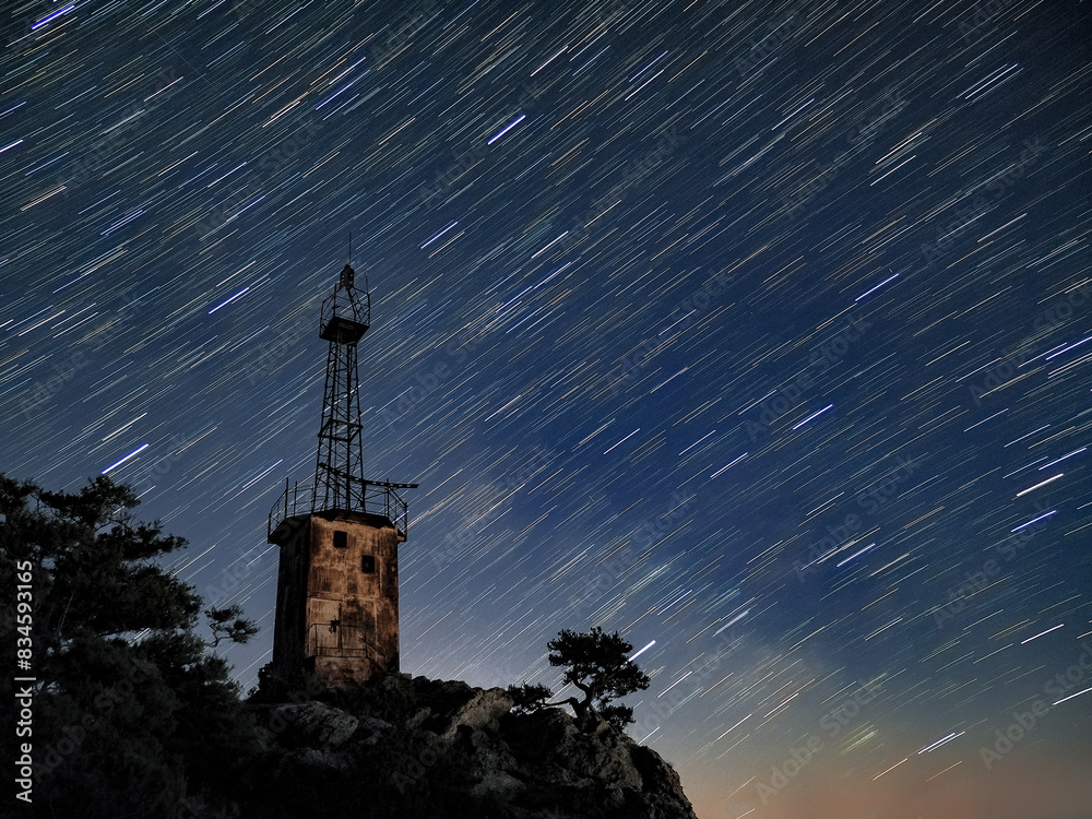 lighthouse under scarry sky at night astrophotography