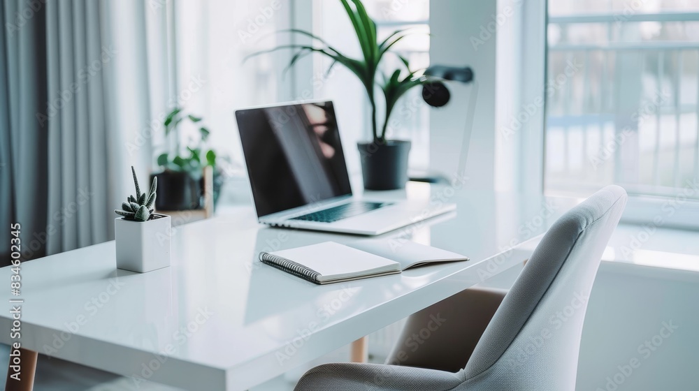 A minimalist office setup with a sleek white desk, a modern chair, and a laptop. The desk has a clean surface with only a plant and a notebook. The background is a bright room with white walls and a A minimalist office setup with a sleek white desk, a modern chair, and a laptop. The desk has a clean surface with only a plant and a notebook. The background is a bright room with white walls and a