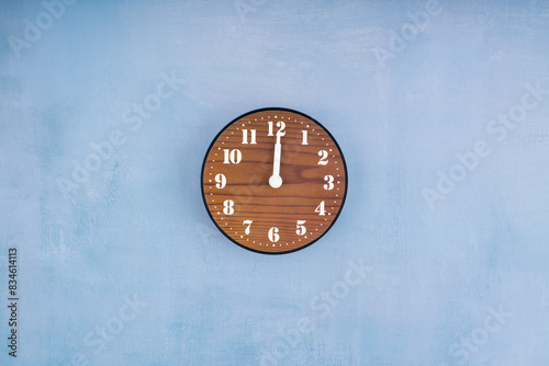 Close up brown wooden clock placed in middle of blue cement. © gamjai