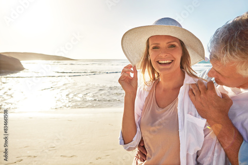 Mature, portrait and happy couple with beach sunset for love or bonding together in nature. Man, woman or lovers with smile in joy for outdoor sunshine, summer or holiday by water, sea or ocean coast © peopleimages.com