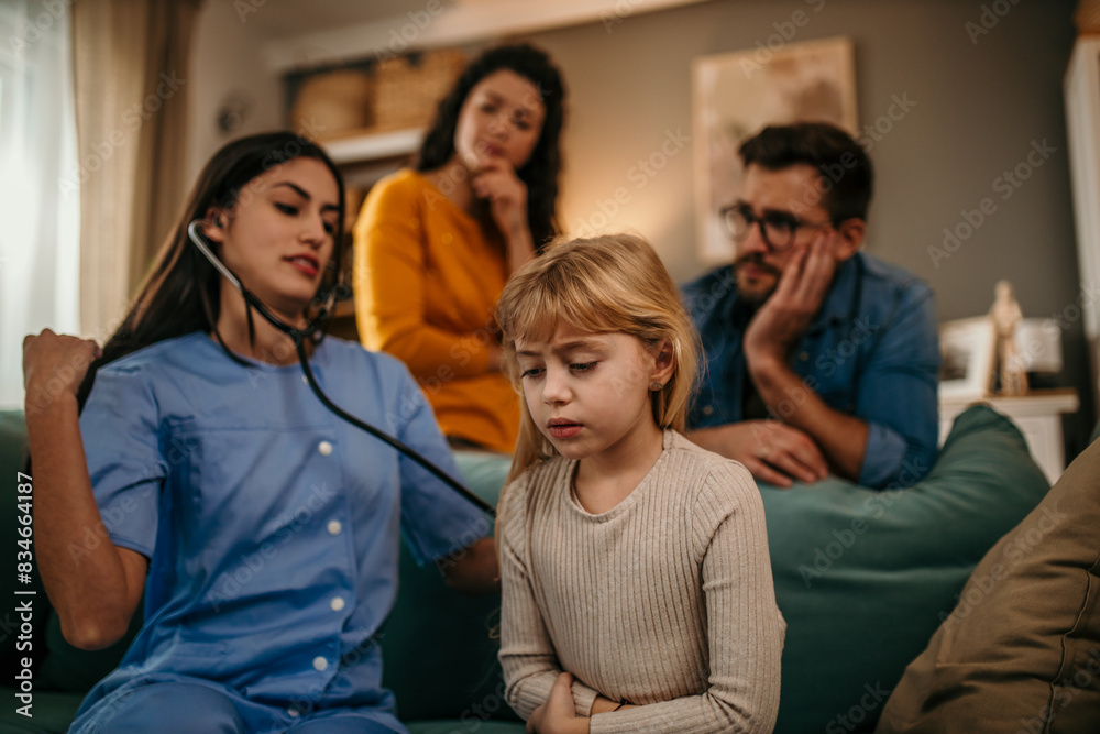 Doctor woman examining little girl with stethoscope in couch Doctor woman examining little girl with stethoscope in couch