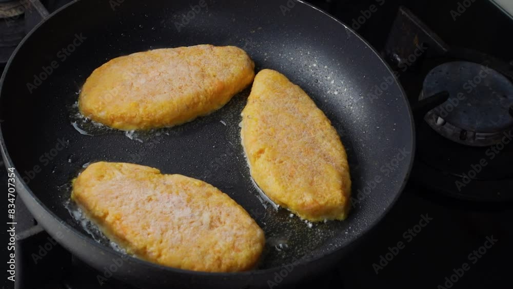 Fish cutlets sizzling in oil while frying in a pan on the stove. Concept of home cooking, traditional recipes, and culinary preparation. Fish cutlets sizzling in oil while frying in a pan on the stove. Concept of home cooking, traditional recipes, and culinary preparation.