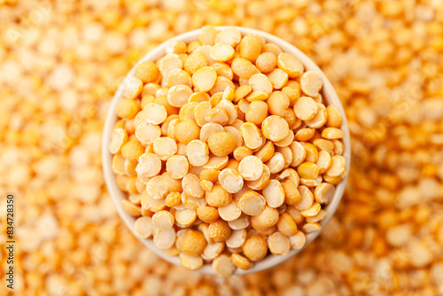 Uncooked, split, yellow peas in bowl. Dry peas grains. Top view