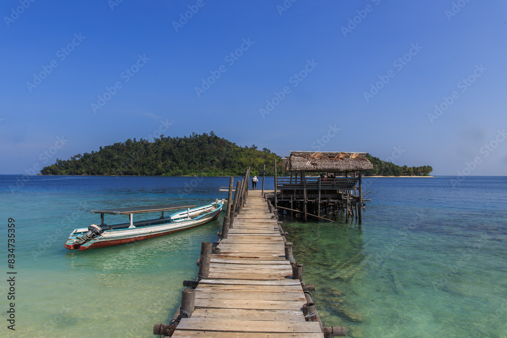 Fototapeta premium Inviting Tropical Jetty Extending into Crystal Clear Waters with Idyllic Island Views Beyond ; indonesia tourism