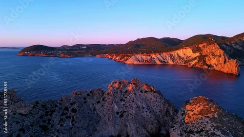 Aerial view of sun setting behind Es Vedra Ibiza during sunset. Showing ocean and clear skies. photo