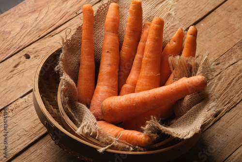 fresh carrots in a woven bamboo container lined with burlap. wortel. 