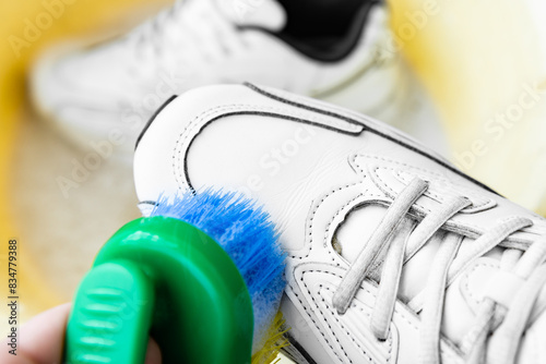 Close up of cleaning white sneakers with a brush and detergent in a basin. © Natallia