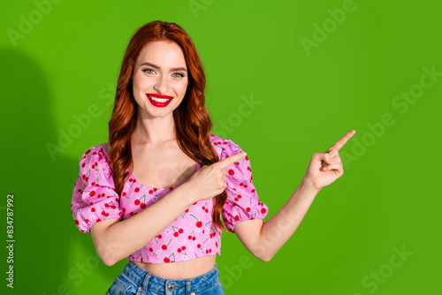 Photo of adorable lovely girl wear pink blouse pointing two fingers empty space isolated green color background