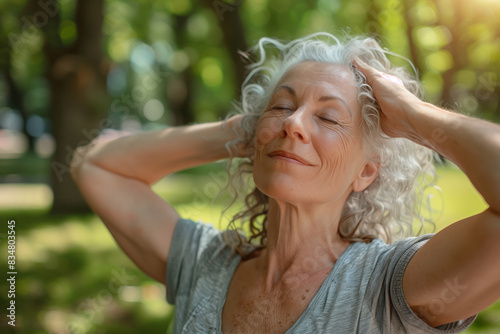 Old people and wellness. Senior woman practices deep breathing in the park on a sunny day photo