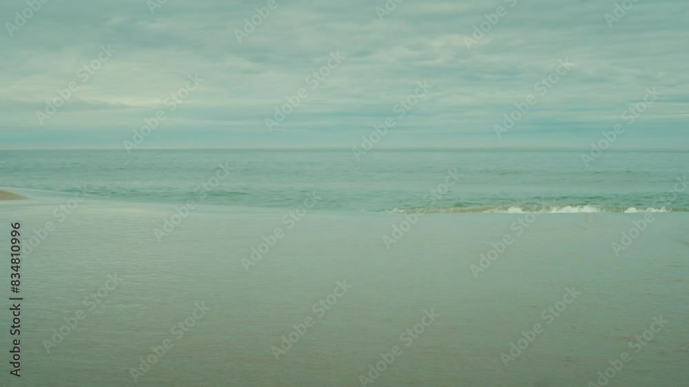 Slow panning shot of small waves rippling onto the shore at Borestranda, Norway Slow panning shot of small waves rippling onto the shore at Borestranda, Norway