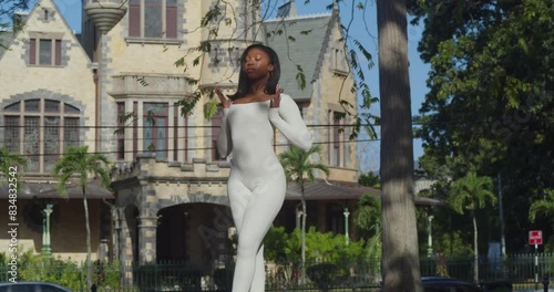 A young girl in a white bodysuit enjoys a city day with Stollmeyer castle in the backdrop. photo