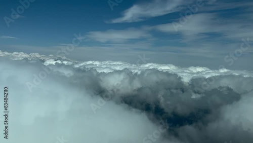 POV cloudscape shot from an airplane cockpit in a left turn over some flufly clouds. Immersive pilot view. Late afternoon light. 4K 60FPS. photo