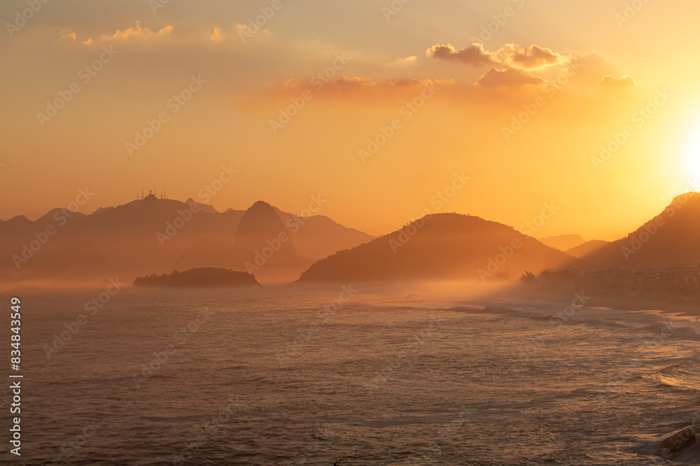a view of a sunset with mountains in the distance and ocean a view of a sunset with mountains in the distance and ocean