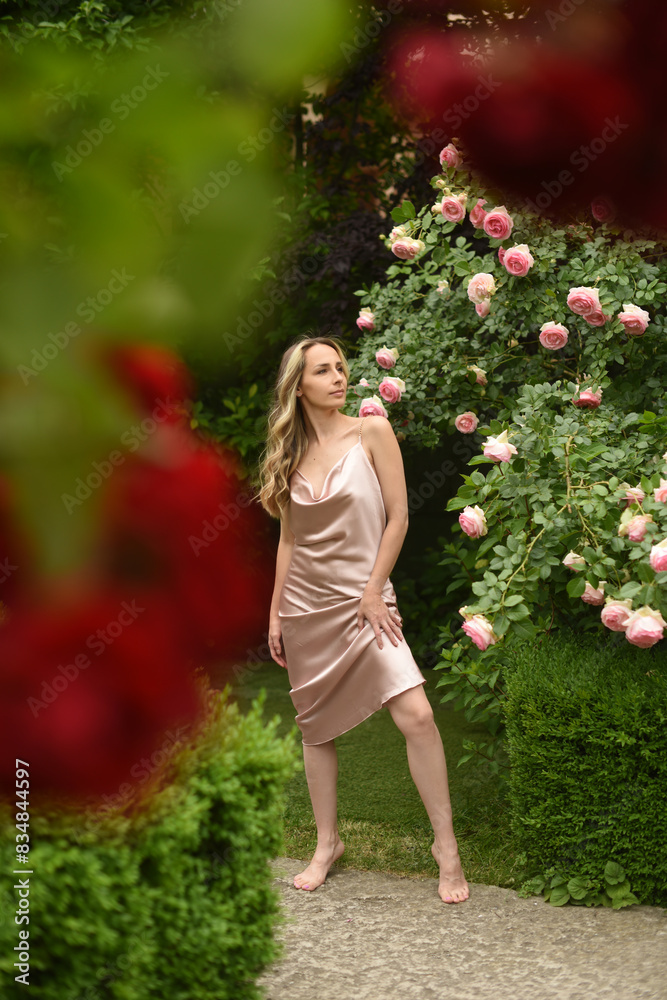 Portrait of a beautiful young woman with long blond hair. Woman in the garden, girl in pink silk dress Portrait of a beautiful young woman with long blond hair. Woman in the garden, girl in pink silk dress