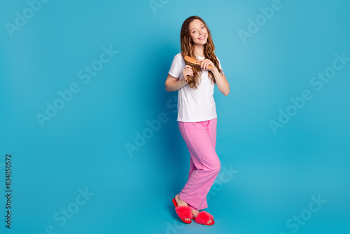 Photo of adorable lovely cute girl wear stylish pajama brush hair daily routine isolated on blue color background