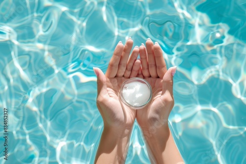 female hands holding a jar of cream against the background of blue pool water, mock up, spf, moisturizing cream for the summer