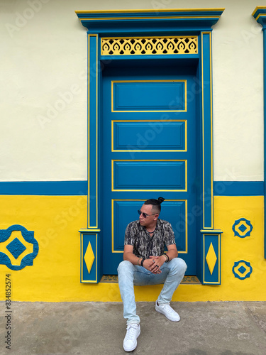 Man Sitting in Front of Vibrant Colonial Doorway