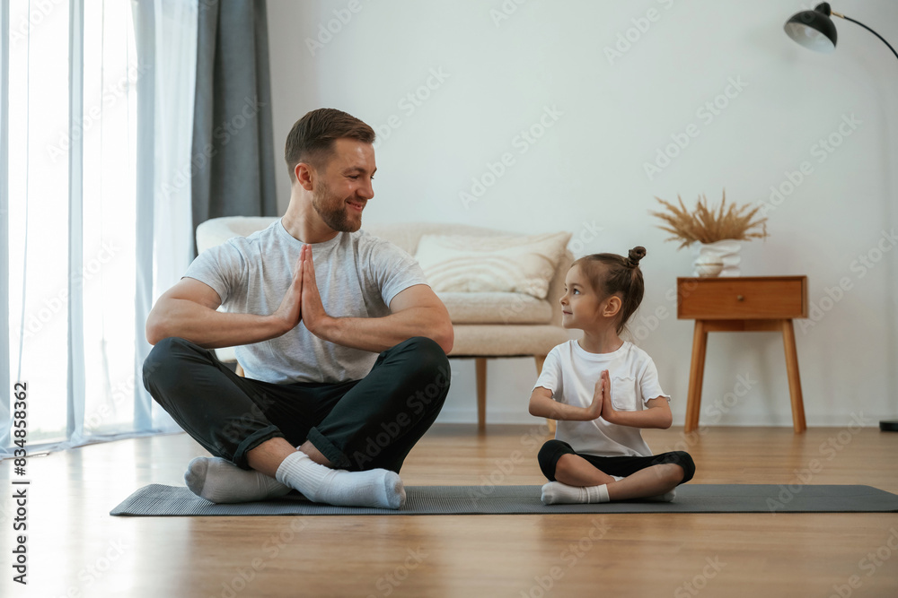 Father with little daughter are doing yoga at home Father with little daughter are doing yoga at home