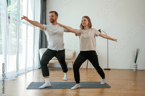 Warrior asana. Man and woman are doing yoga exercises at home