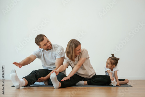 Family of mother, father and daughter are doing yoga at home