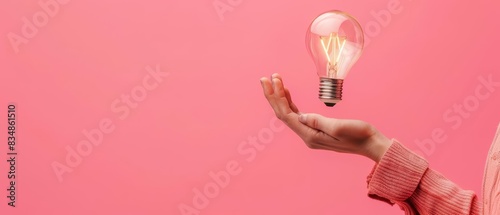 A human hand holding a pseudobulb against a solid color backdrop with copy space photo