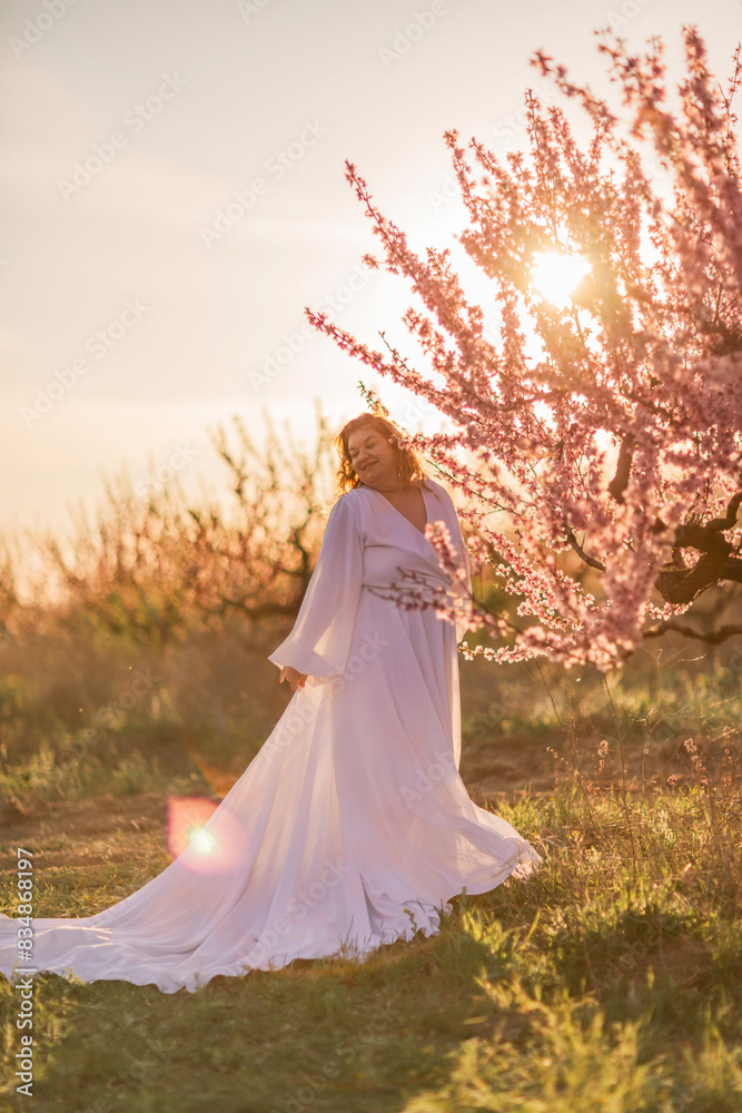 Woman blooming peach orchard. Against the backdrop of a picturesque peach orchard, a woman in a long white dress enjoys a peaceful walk in the park, surrounded by the beauty of nature. Woman blooming peach orchard. Against the backdrop of a picturesque peach orchard, a woman in a long white dress enjoys a peaceful walk in the park, surrounded by the beauty of nature.