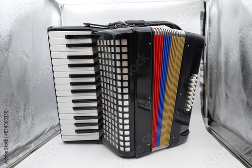 A classic black Colombian accordion adorned with vibrant red, yellow, and blue stripes representing the Colombian flag. This traditional musical instrument is essential in Colombian folk music