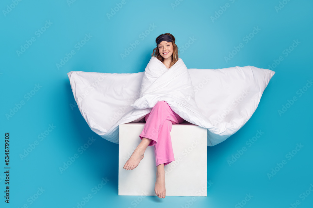 Photo of sweet lovely cute girl wear white stylish pajama sitting cube isolated on blue color background Photo of sweet lovely cute girl wear white stylish pajama sitting cube isolated on blue color background