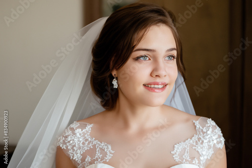 girl bride. happy young girl with a hairstyle stands in a white wedding dress on a dark background, close-up holiday concept