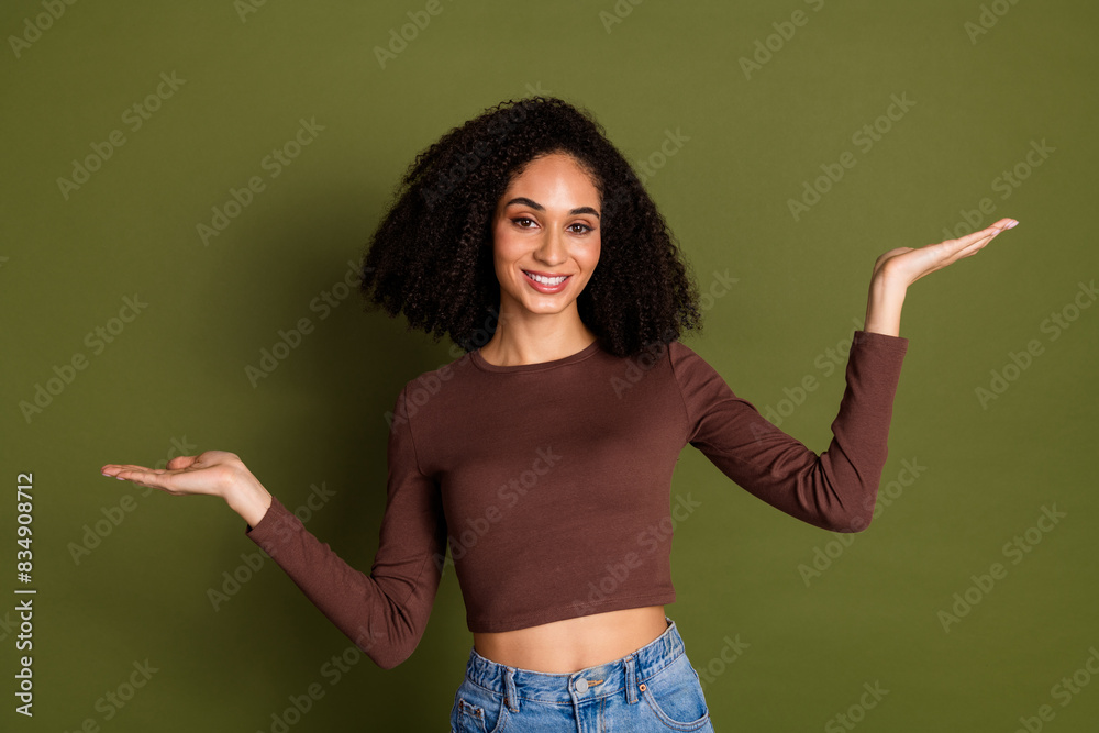 Photo portrait of pretty young girl compare hold empty space wear trendy brown outfit isolated on khaki color background Photo portrait of pretty young girl compare hold empty space wear trendy brown outfit isolated on khaki color background