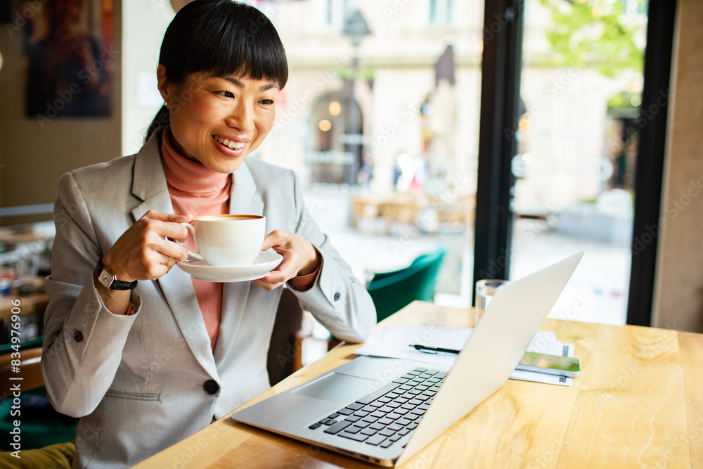 Businesswoman enjoying coffee while working on laptop in cafe Businesswoman enjoying coffee while working on laptop in cafe