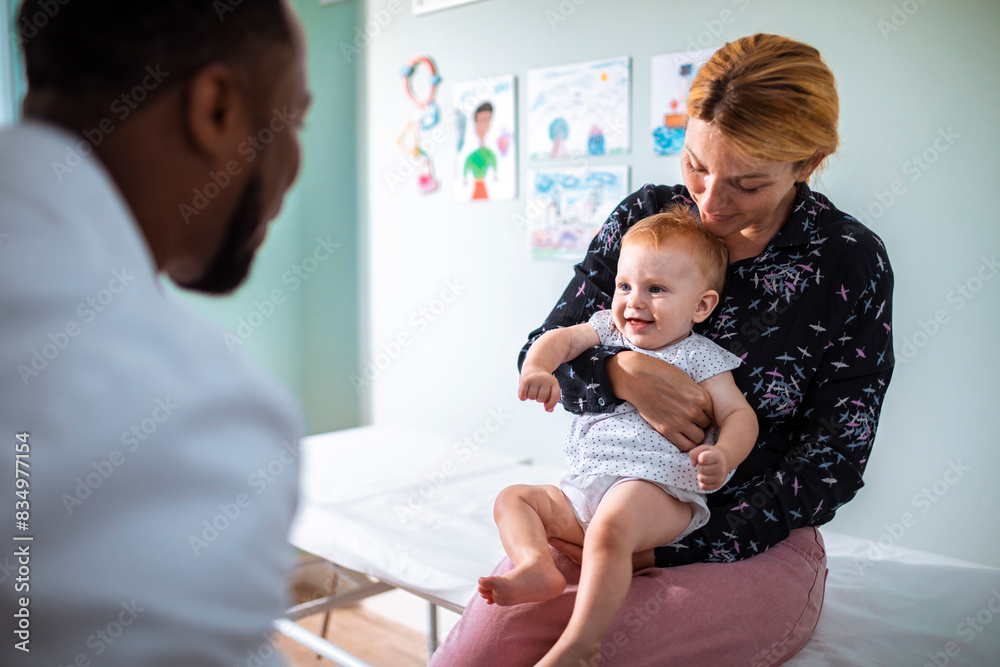 Doctor interacting with baby held by mother in pediatric clinic Doctor interacting with baby held by mother in pediatric clinic
