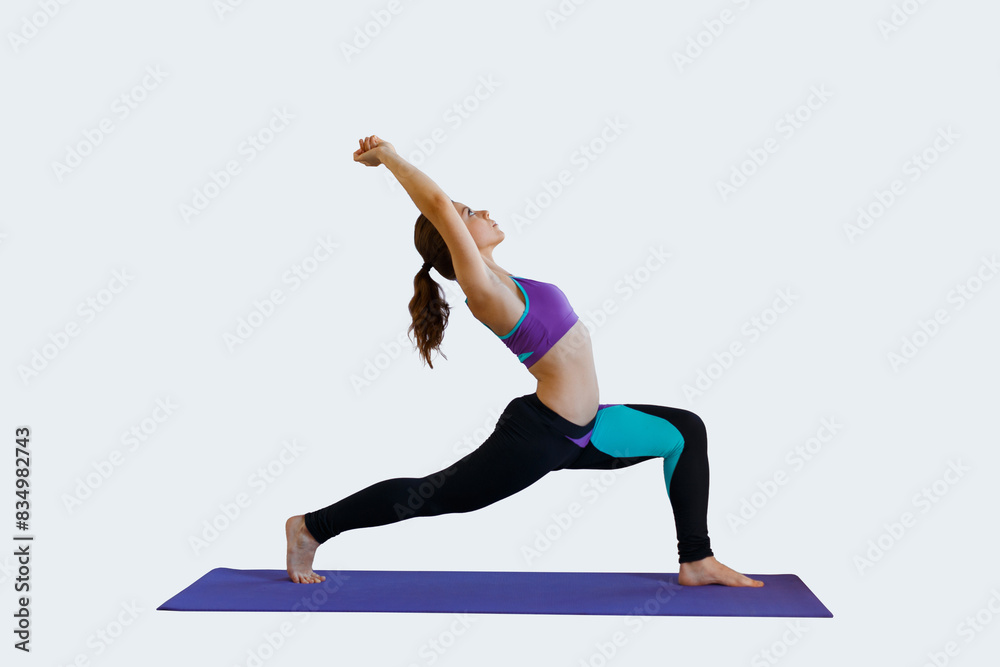 Beautiful young woman model in fashion clothes doing warm-up on a mat isolated on a light background Beautiful young woman model in fashion clothes doing warm-up on a mat isolated on a light background