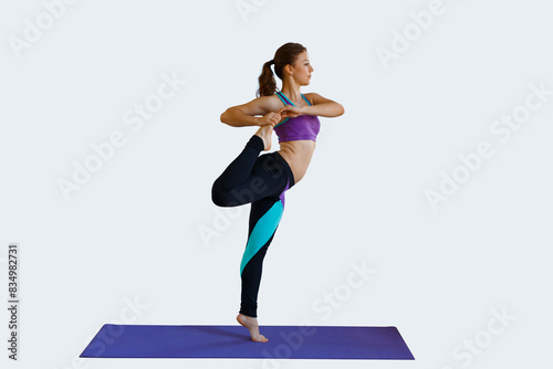 Beautiful fitness girl doing warm-up and stretching her legs on a light background