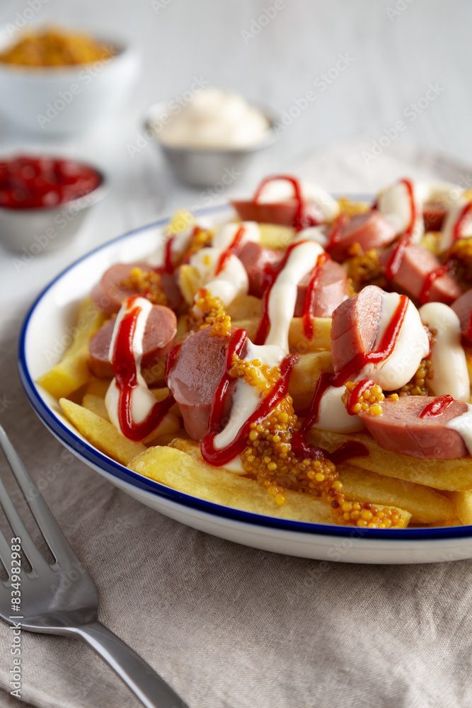 Homemade Salchipapa Fries with Ketchup, Mustard and Mayo on a Plate, low angle view. Close-up. Homemade Salchipapa Fries with Ketchup, Mustard and Mayo on a Plate, low angle view. Close-up.