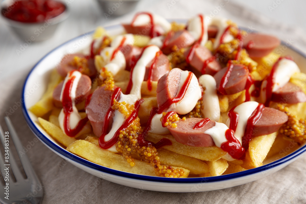 Homemade Salchipapa Fries with Ketchup, Mustard and Mayo on a Plate, low angle view. Close-up. Homemade Salchipapa Fries with Ketchup, Mustard and Mayo on a Plate, low angle view. Close-up.