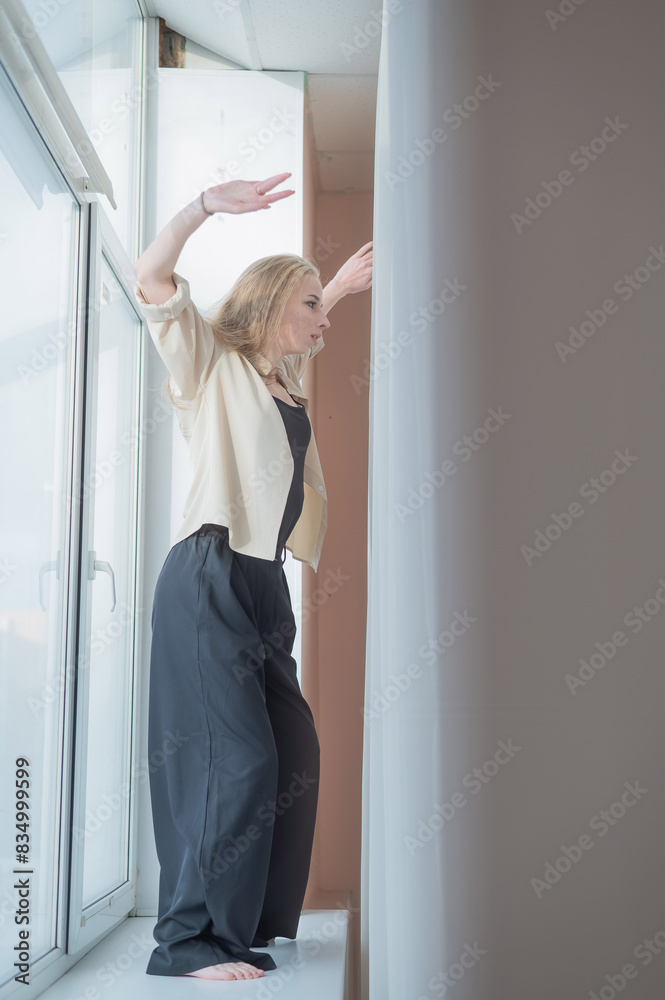 Caucasian woman dancing modern dance on the windowsill. Vertical photo. Caucasian woman dancing modern dance on the windowsill. Vertical photo.