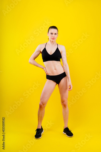 Fit sportswoman in leggings and sports bra looking away and while standing on yellow red